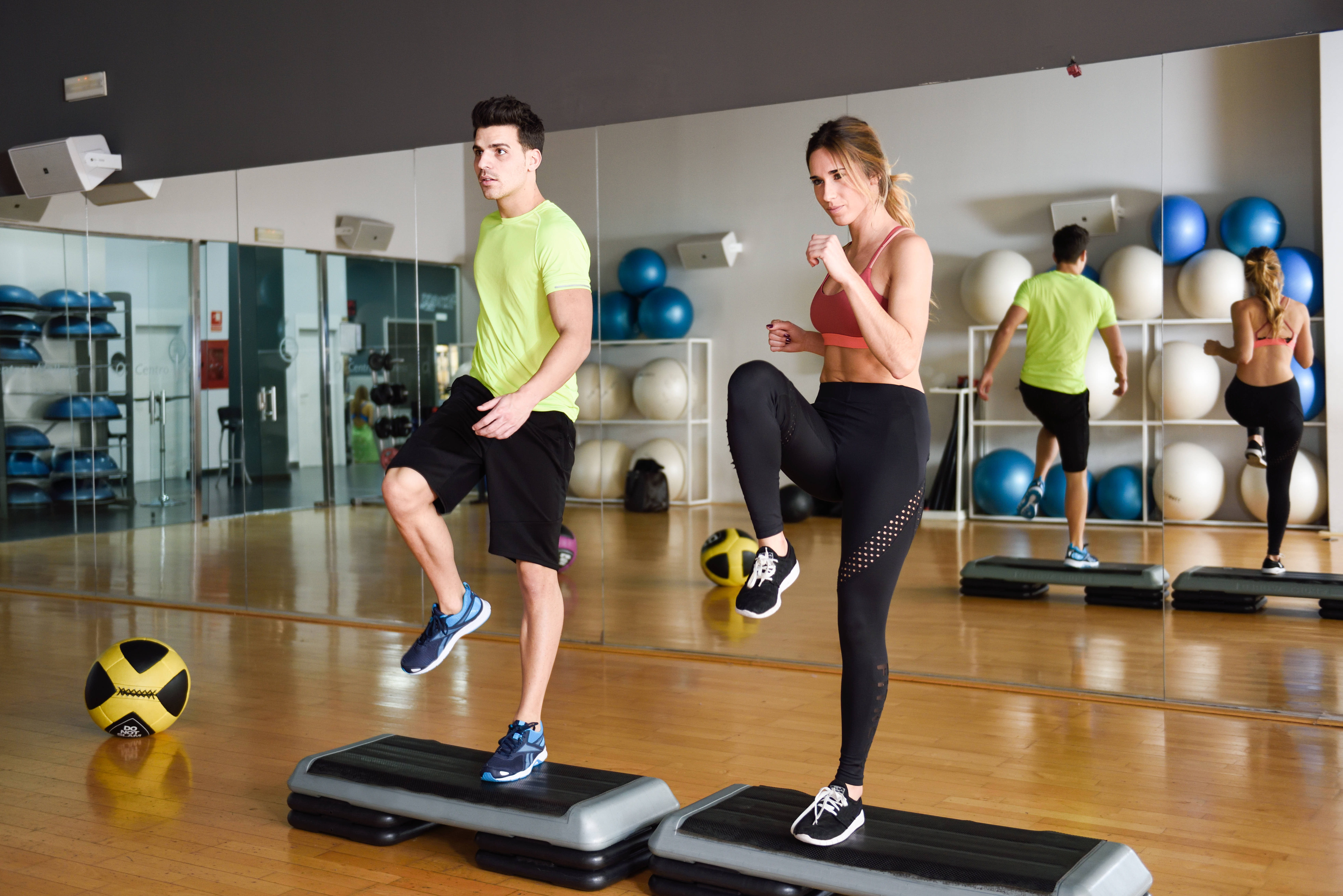 Two people working out with steppers in gym. Man and woman wearing sportswear clothes.